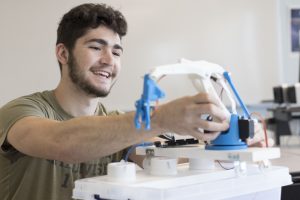 Smiling Engineering Student with Automated Shellfish Upweller Model